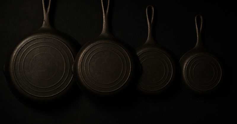 A row of vintage skillet undersides showing casting texture and heat rings