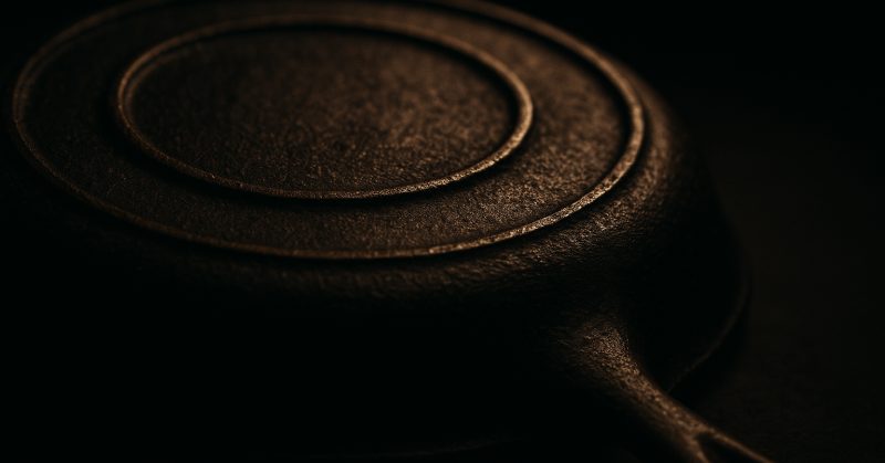 The underside of a vintage skillet at a low angle, showing raised casting detail